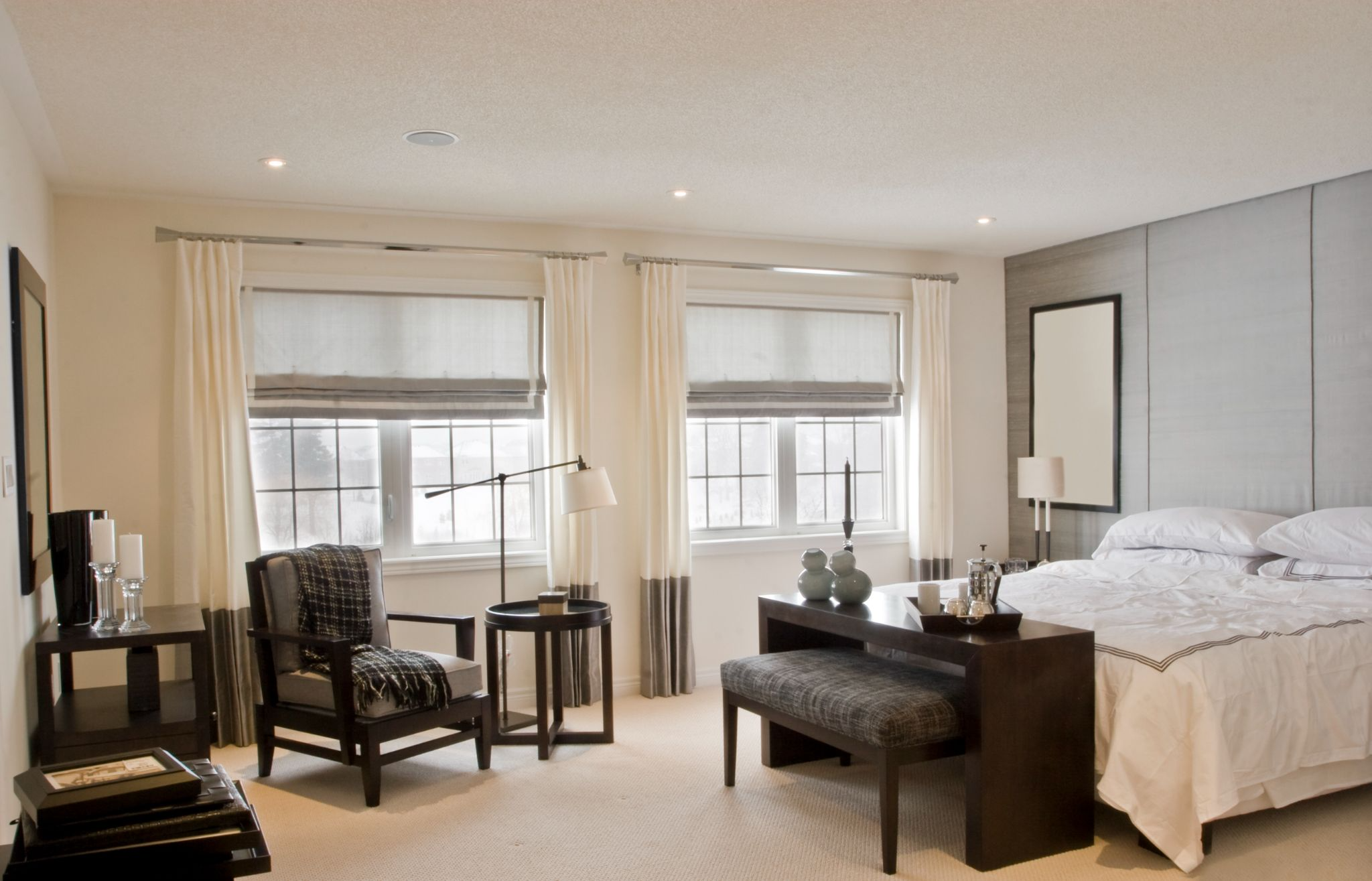 Roman shades and curtains being paired in bedroom to create a layered look