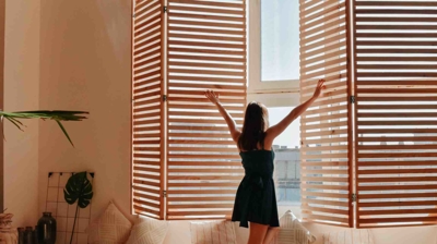 woman from behind opening window shutters