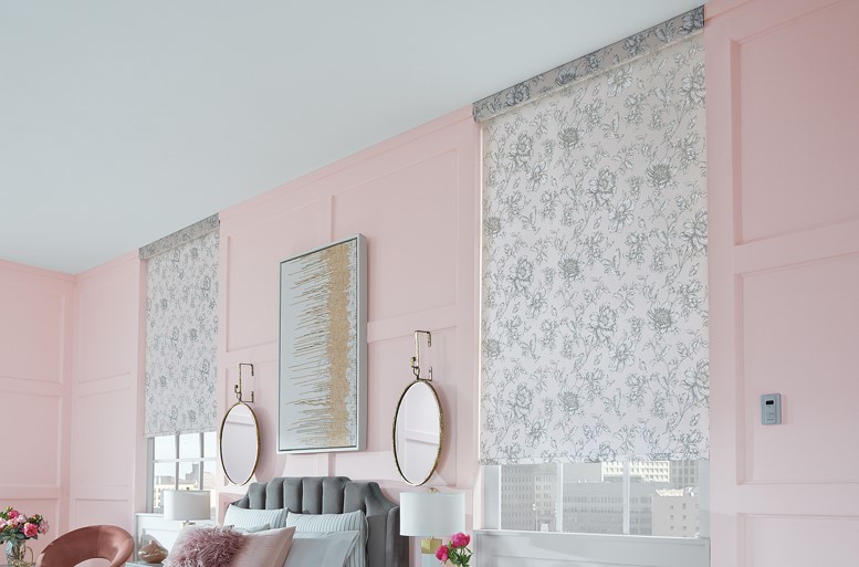 Pink bedroom with two large windows on each side of bed. Windows have roller shades with a grey design on them.